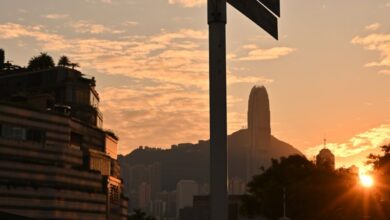 Popular Photography - Captivating sunset over Hong Kong skyline with a prominent street sign in the foreground.