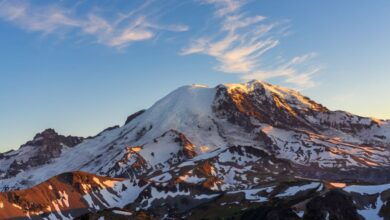 National Park Photography - A stunning view of snow-covered Mount Rainier illuminated by the setting sun's warm glow.