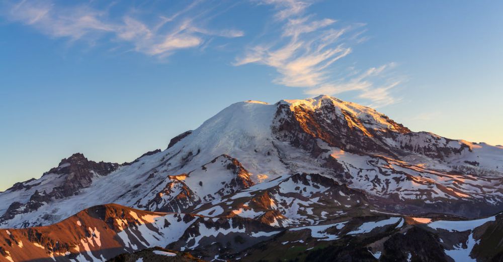 National Park Photography - A stunning view of snow-covered Mount Rainier illuminated by the setting sun's warm glow.