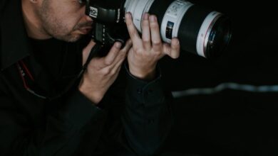 Lens Choice - Focused male photographer using DSLR camera with telephoto lens in studio.