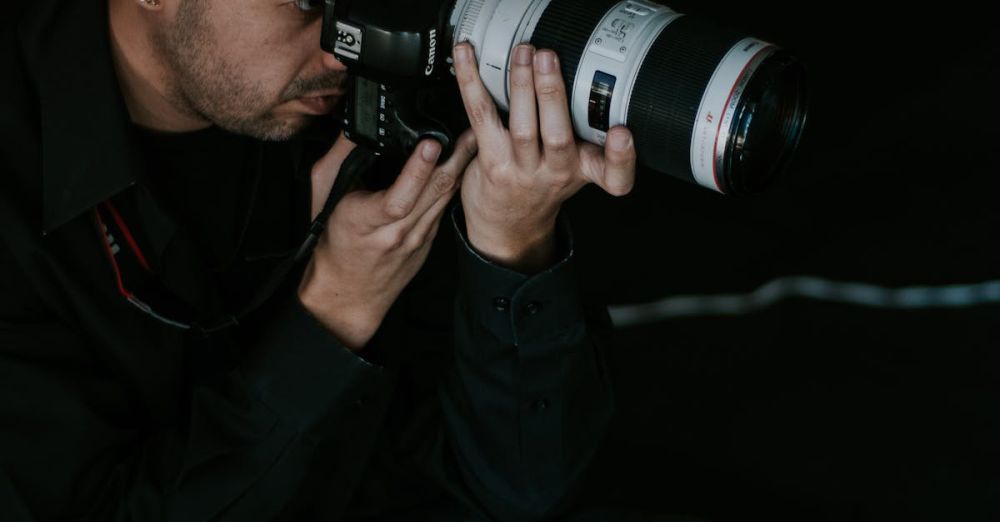 Lens Choice - Focused male photographer using DSLR camera with telephoto lens in studio.