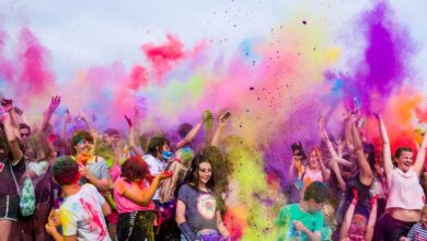 Festivals - A joyful crowd covered in vivid colors celebrates a festival outdoors with flying powder.