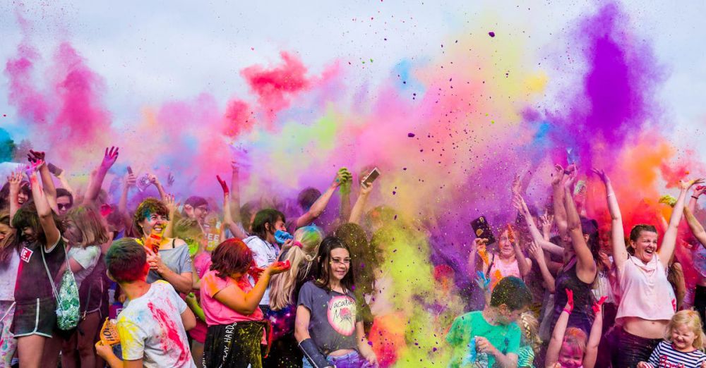 Festivals - A joyful crowd covered in vivid colors celebrates a festival outdoors with flying powder.