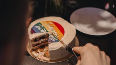Food Festivals - A person slices a rainbow-decorated cake indoors, capturing a warm celebratory moment.