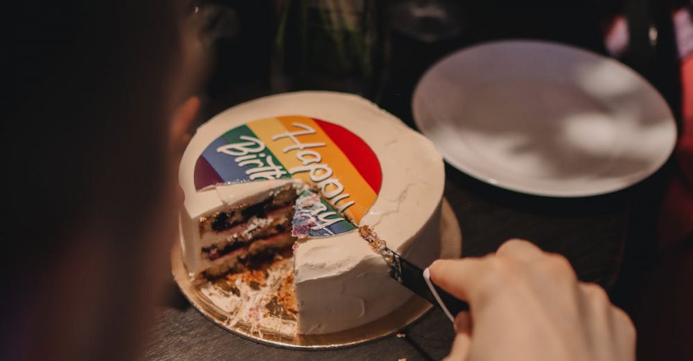 Food Festivals - A person slices a rainbow-decorated cake indoors, capturing a warm celebratory moment.