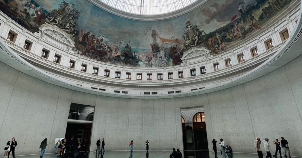 Art Lovers - Majestic interior showcasing a grand dome with artwork and reflections on polished floors.