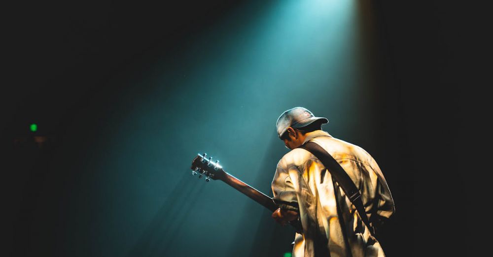 Rock Music Festivals - A musician performing live on stage under dramatic lighting, playing a guitar.