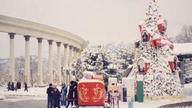 City Festivals - Snow-covered Christmas scene featuring a festive tree and colonnades in winter.