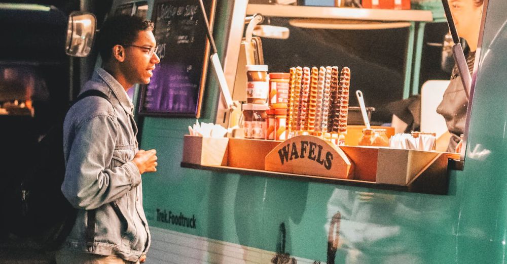 Food Trucks - A customer waits at a vibrant waffle food truck in Weert, Netherlands at night.