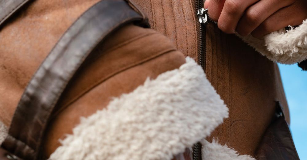 Zip Lining Experiences - Close-up of hands zipping a warm shearling-lined suede jacket.