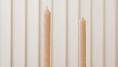 Holders - Elegant minimalist candles with unique holders against a striped wall, perfect for decorating ideas.