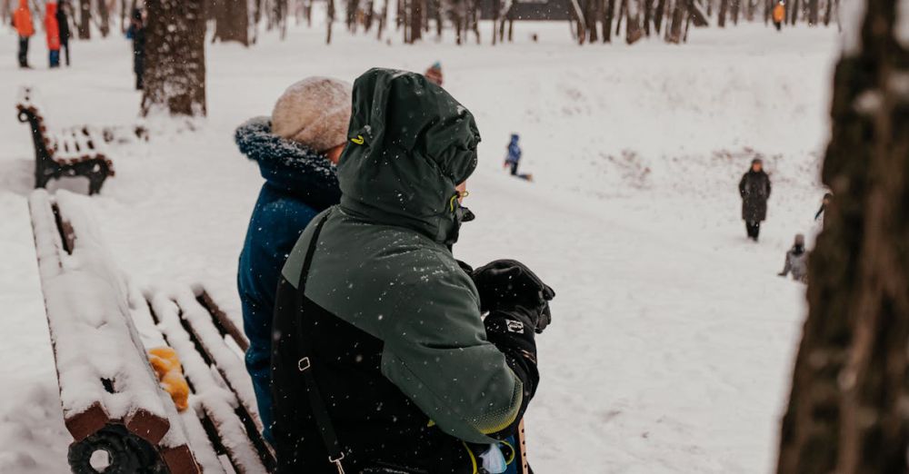 Outdoor Activities - Two people sit warmly bundled on a snowy park bench in winter.