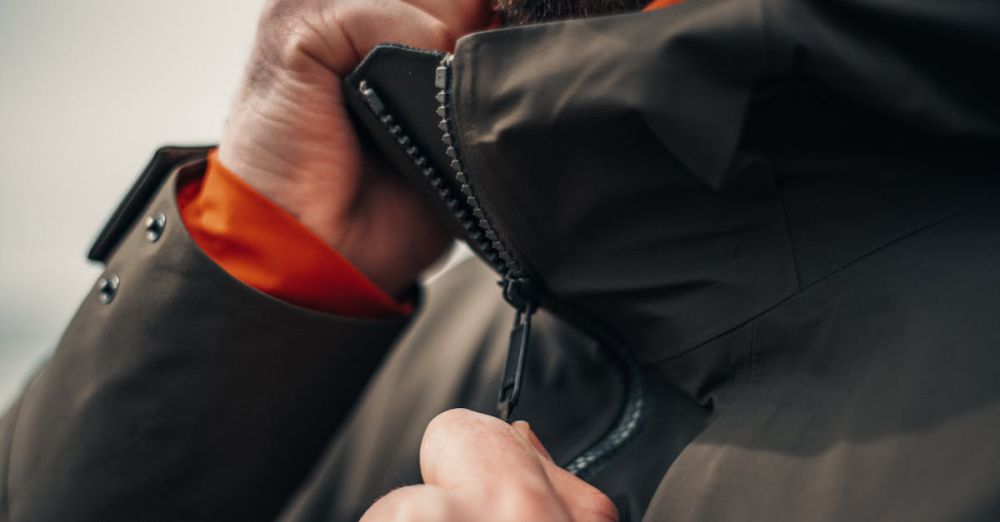 Winter Zip Lining - Close-up of a man zipping up his winter jacket outdoors, focusing on hands and zipper detail.