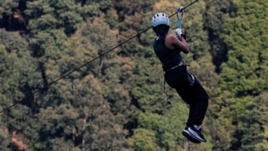 Mountain Zip Lining - An adult man ziplining through the dense forest of Villa del Carbón in daylight.