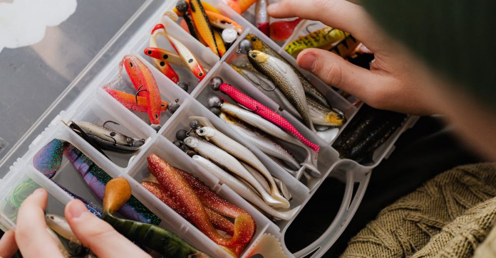 Fishing Trip Preparation - Hands organizing assorted fishing lures in a plastic box.