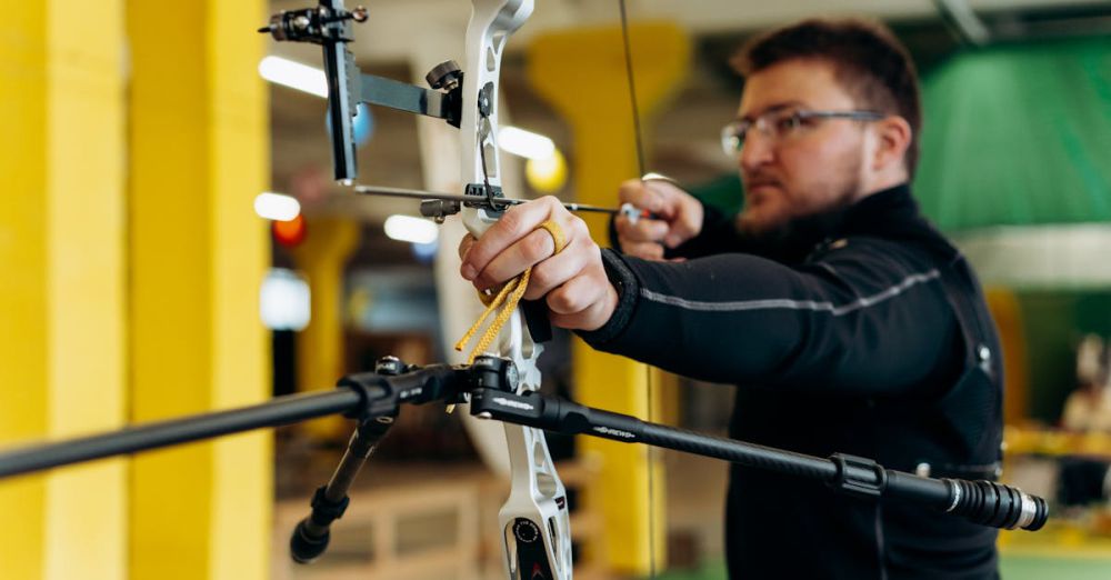 Big Game Hunting - Man concentrating on aiming during an indoor archery practice session.