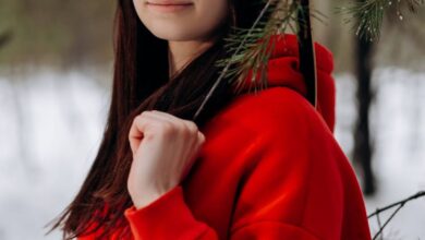 Family Hunting - Portrait of a young woman in a red hoodie holding a bow in a snowy forest setting.