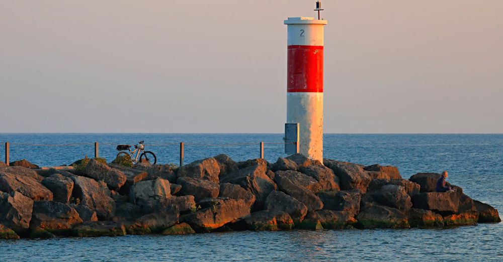 Ontario Fishing - A calming scene of sunrise at Webster's lighthouse with rocks and a bicycle.