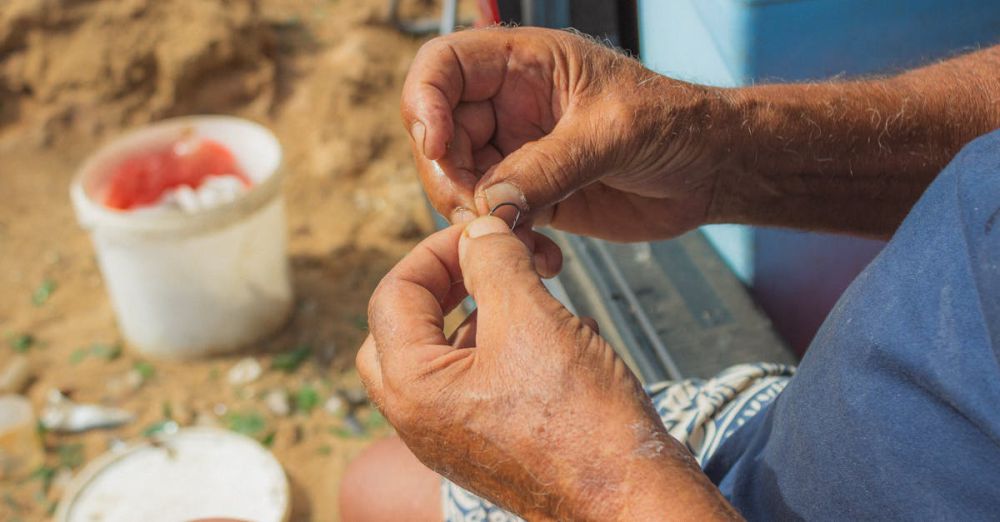 Expert Fishing - Close-up of a senior man preparing a fishing line on a beach, showcasing skilled hands.