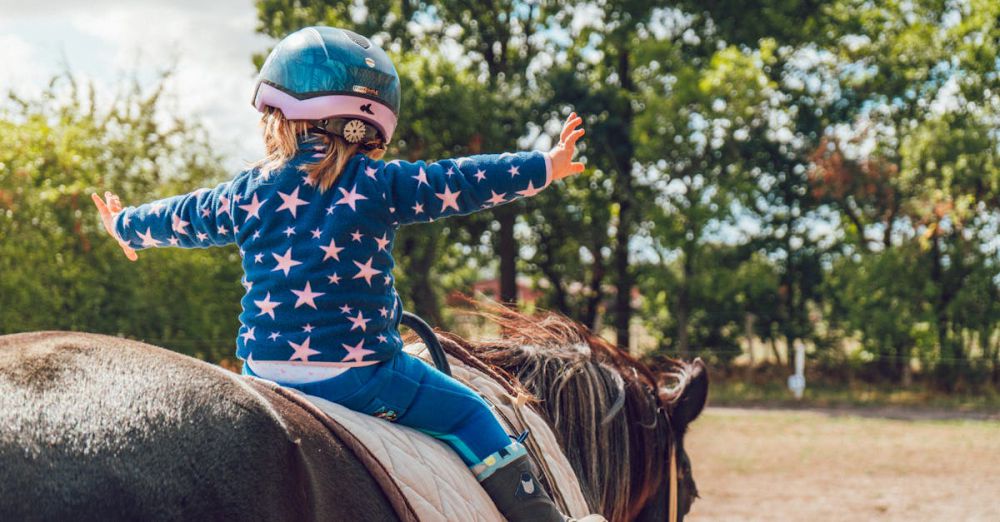 Horseback Riding - A child confidently rides a horse outdoors, wearing a helmet and star-patterned jacket.