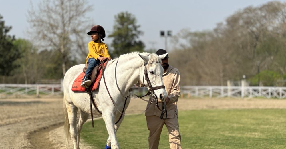 Beginner Horseback Riding - A young child enjoys a horseback ride with guidance in a serene Islamabad park setting.