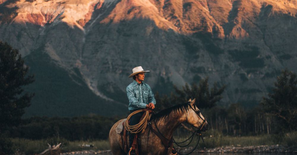 Scenic Views Horseback Riding - A cowboy rides his horse across a scenic river in Waterton Park, Canada with mountainous backdrop.