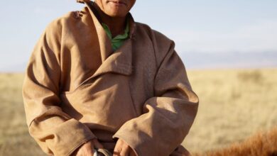 Experienced Riders - Elderly Mongolian horseman rides through the tranquil steppe.