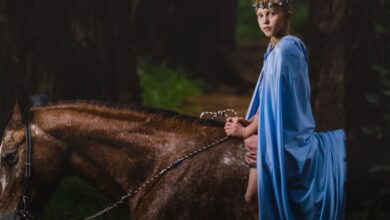 Kids Horseback Riding - A young child in a blue cloak rides a horse through a mysterious forest setting.