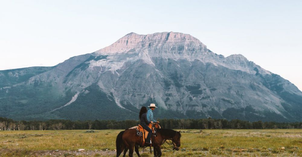 Mountain Horseback Riding - A person rides a horse through a meadow with stunning mountain views in Waterton Park.