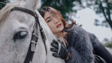 National Park Horseback Riding - Stylish woman on horseback in natural setting, showcasing elegant fashion and thoughtful expression.