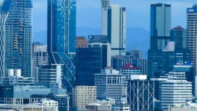Tallest Waterfalls - Panoramic view of Auckland city skyline, highlighting the iconic Sky Tower against a cloudy sky.