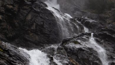 Hidden Waterfalls - A foggy waterfall cascades down rocky terrain, creating a serene natural scene.