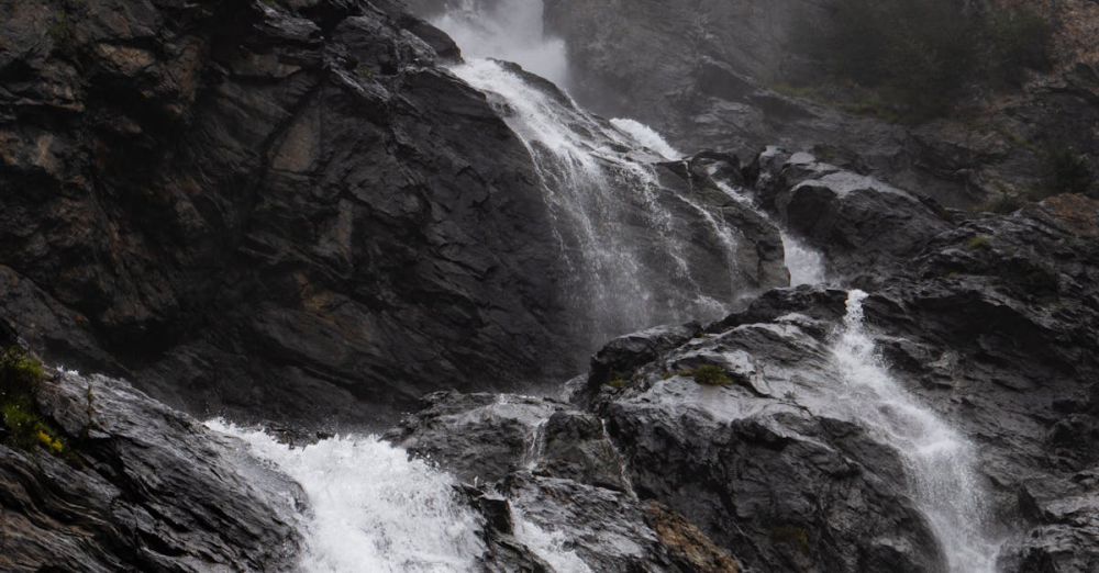 Hidden Waterfalls - A foggy waterfall cascades down rocky terrain, creating a serene natural scene.