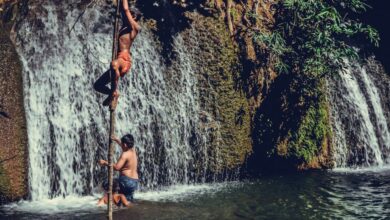 Family Waterfalls - Boys enjoying a summer day climbing near a waterfall in Thailand.