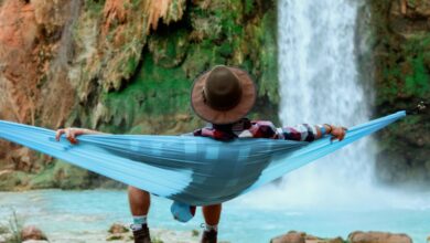 Camping Waterfalls - A person relaxes in a hammock by a waterfall, capturing the essence of tranquil outdoor leisure.