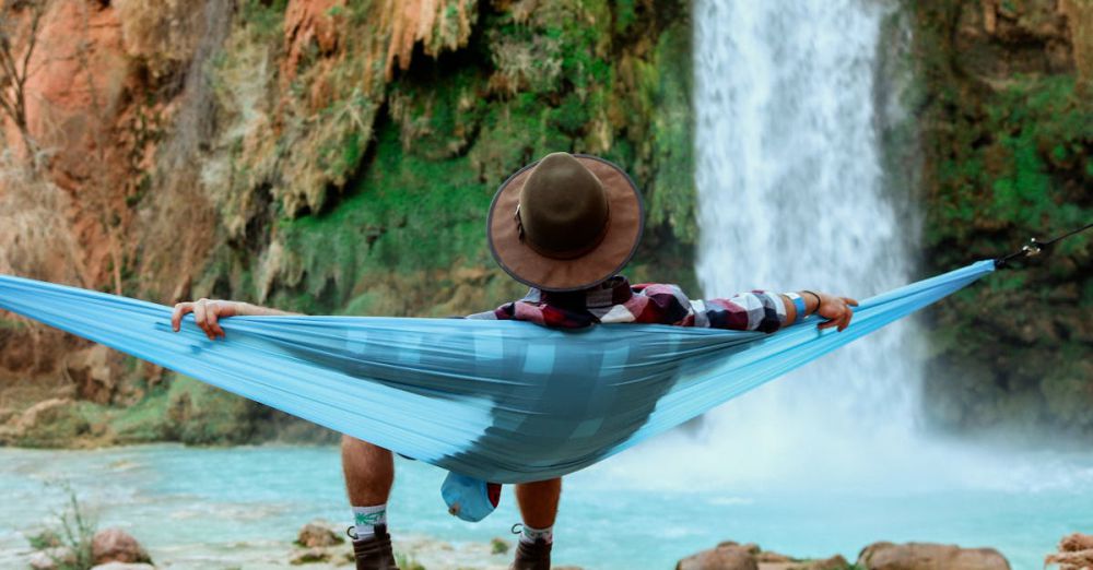 Camping Waterfalls - A person relaxes in a hammock by a waterfall, capturing the essence of tranquil outdoor leisure.