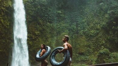 Adventure Waterfalls - A couple in swimwear with float tubes exploring a lush waterfall in Bali, Indonesia.