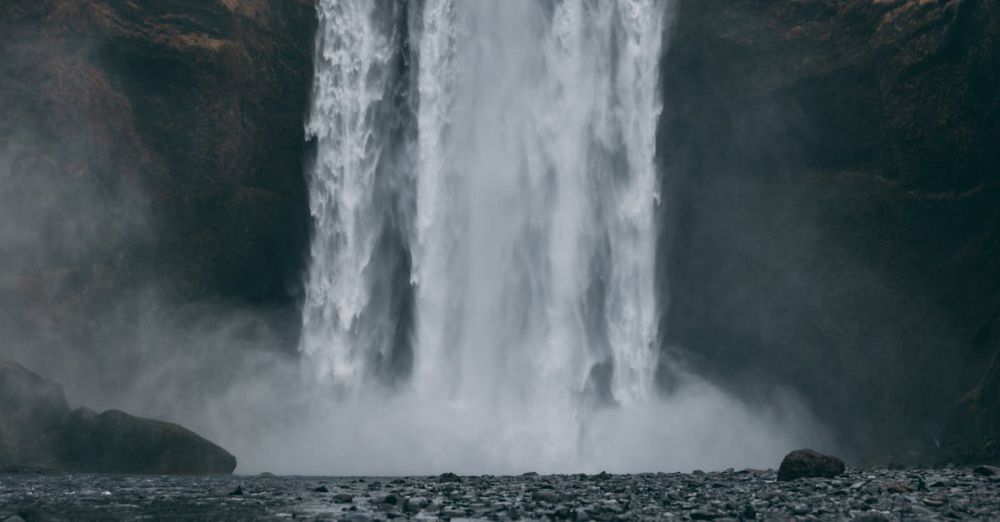 Rockies Waterfalls - Stunning view of Skógafoss waterfall cascading in a dramatic, misty Icelandic landscape.