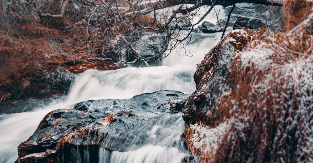 Winter Waterfalls - Serene winter waterfall flows through a snow-covered forest in Bergenhus, Norway.