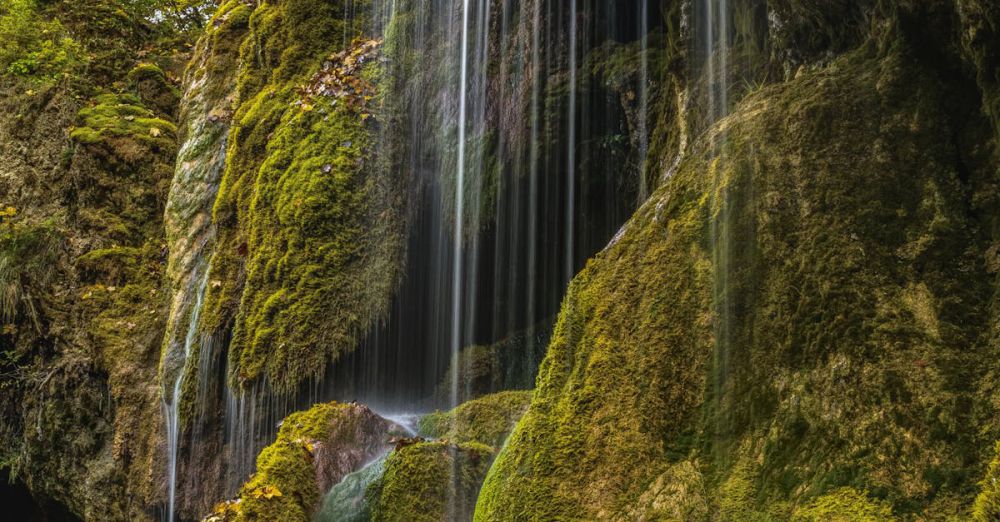 Peaceful Waterfalls - Tranquil waterfall cascading over mossy rocks in a lush forest setting. Perfect nature background.