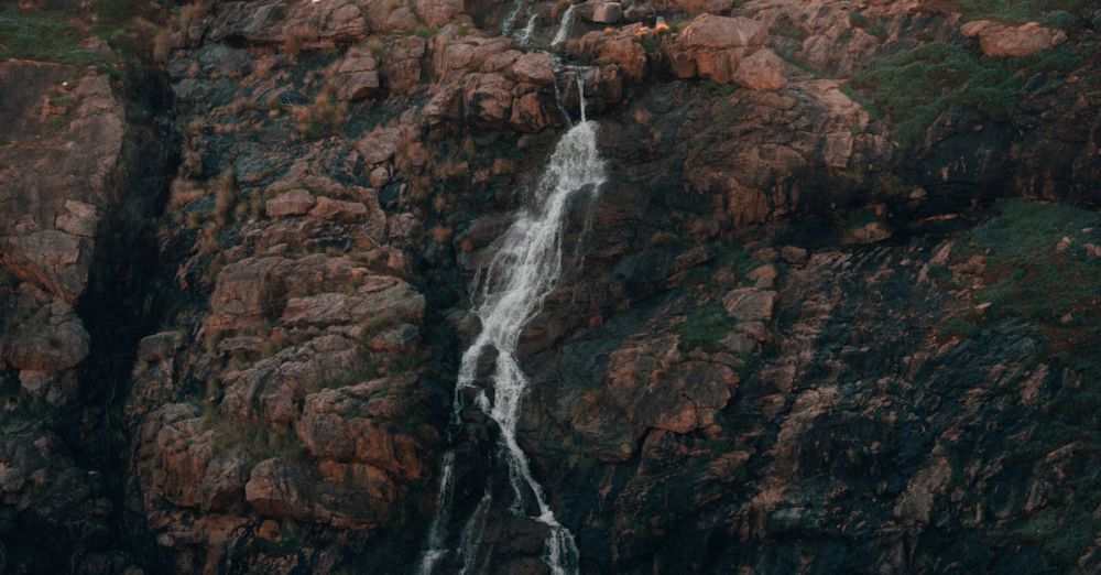 Off The Beaten Path Waterfalls - Breathtaking view of a waterfall cascading down a rocky mountainside in Western Australia.