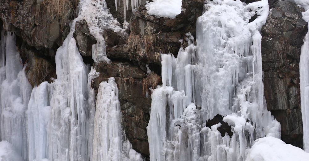 Stunning Waterfalls - Breathtaking view of a frozen waterfall cascading down rocky cliffs during winter.