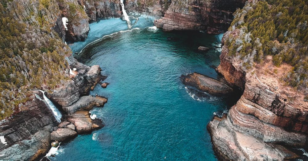 Newfoundland Waterfalls - A breathtaking aerial shot of Flatrock, Canada with cliffs and pristine water.