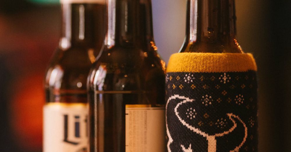 Craft Beer Tours - A warm, inviting image of three beer bottles, one with a sports-themed cozy, set in a casual indoor setting.