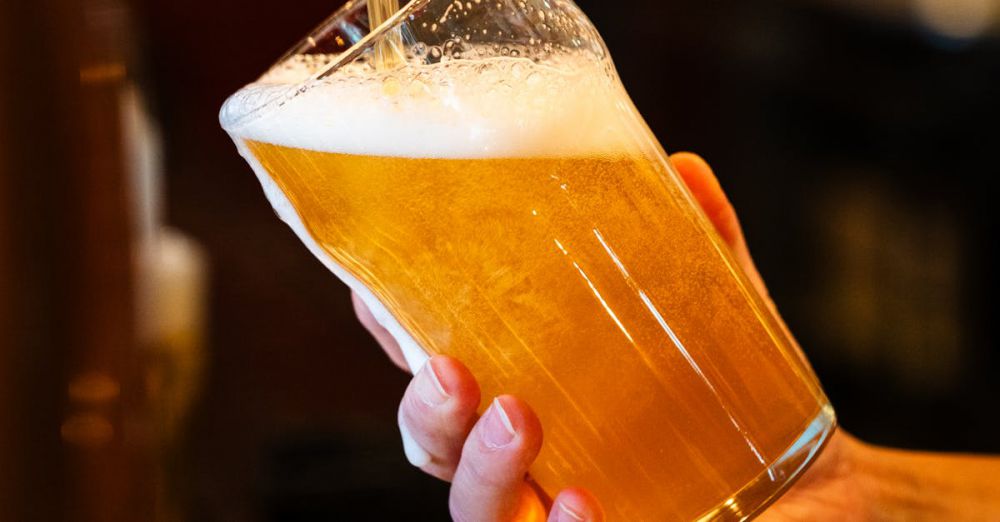 Quebec Vineyard & Brewery Tours - Closeup of a draft beer being poured into a pint glass at a bar in Montreal, Canada.