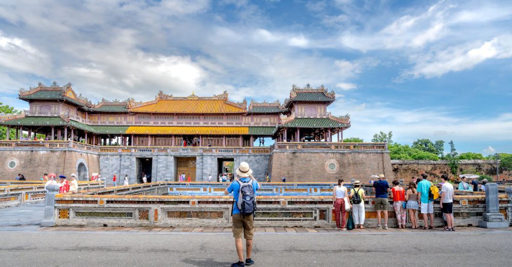 Group Tours - Tourists gather at the Imperial City of Hue, showcasing traditional Vietnamese architecture under a blue sky.