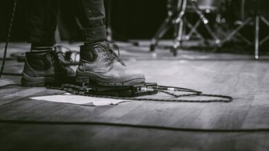 Live Music Tours - Black and white image of a performer using guitar pedal at a live concert.