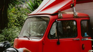 Finding Tours - Man inspecting a classic red truck amid lush greenery in Amalfi, Italy, on a sunny day.