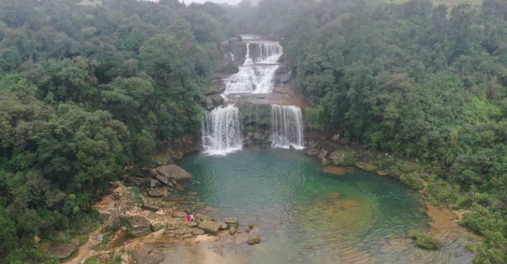 Adventure Tours - Stunning aerial view of a waterfall surrounded by dense jungle in Meghalaya, India.