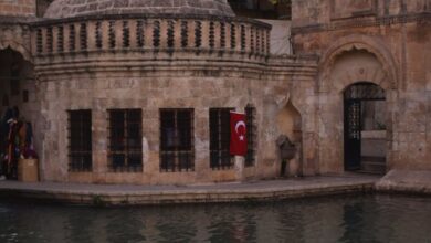 Relaxing Tours - Scenic view of Balikli Gol mosque by the water with Turkish flag.